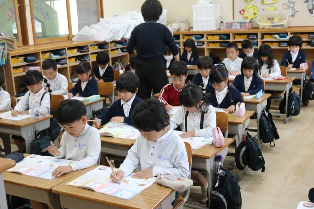 机に向かって字を書く園児たち