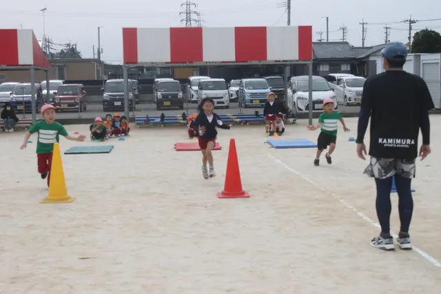 運動場でかけっこをする園児たち